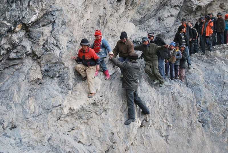 Large group walking across the side of a cliff
